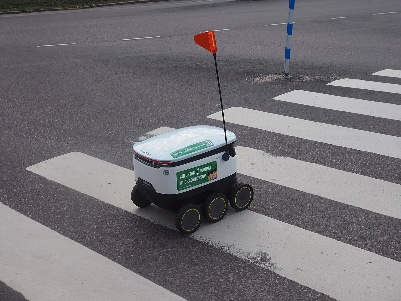 A six-wheeled Starship food-delivery robot crosses a marked street in Loviisa, Finland.