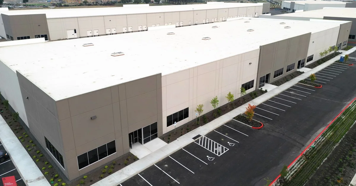 Aerial view of Agility Robotics' large RoboFab humanoid-robot factory building and surrounding parking area in Salem, Oregon