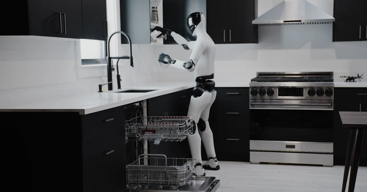 A Figure 03 humanoid robot handling a cup beside an open dishwasher in a modern kitchen during a Helix 02 demonstration