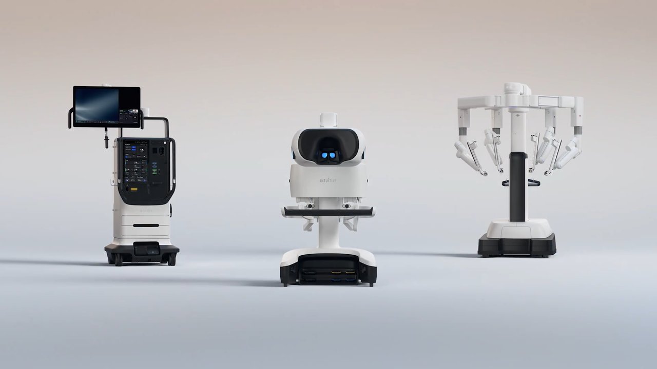 The da Vinci 5 surgical system displayed as a coordinated lineup of its vision cart, surgeon console and patient-side robotic arms