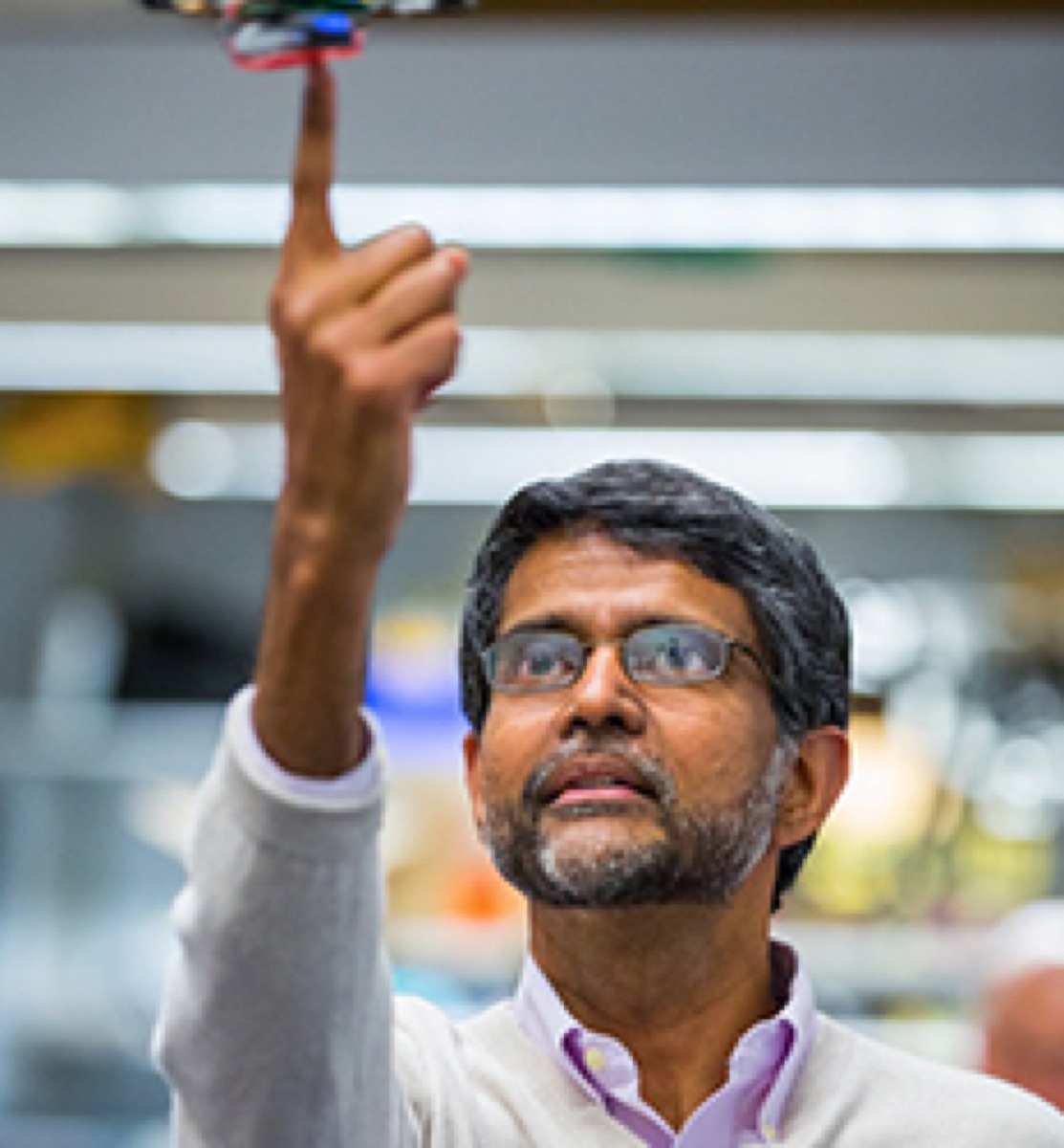 Roboticist Vijay Kumar balancing a small quadrotor on one finger in a robotics laboratory
