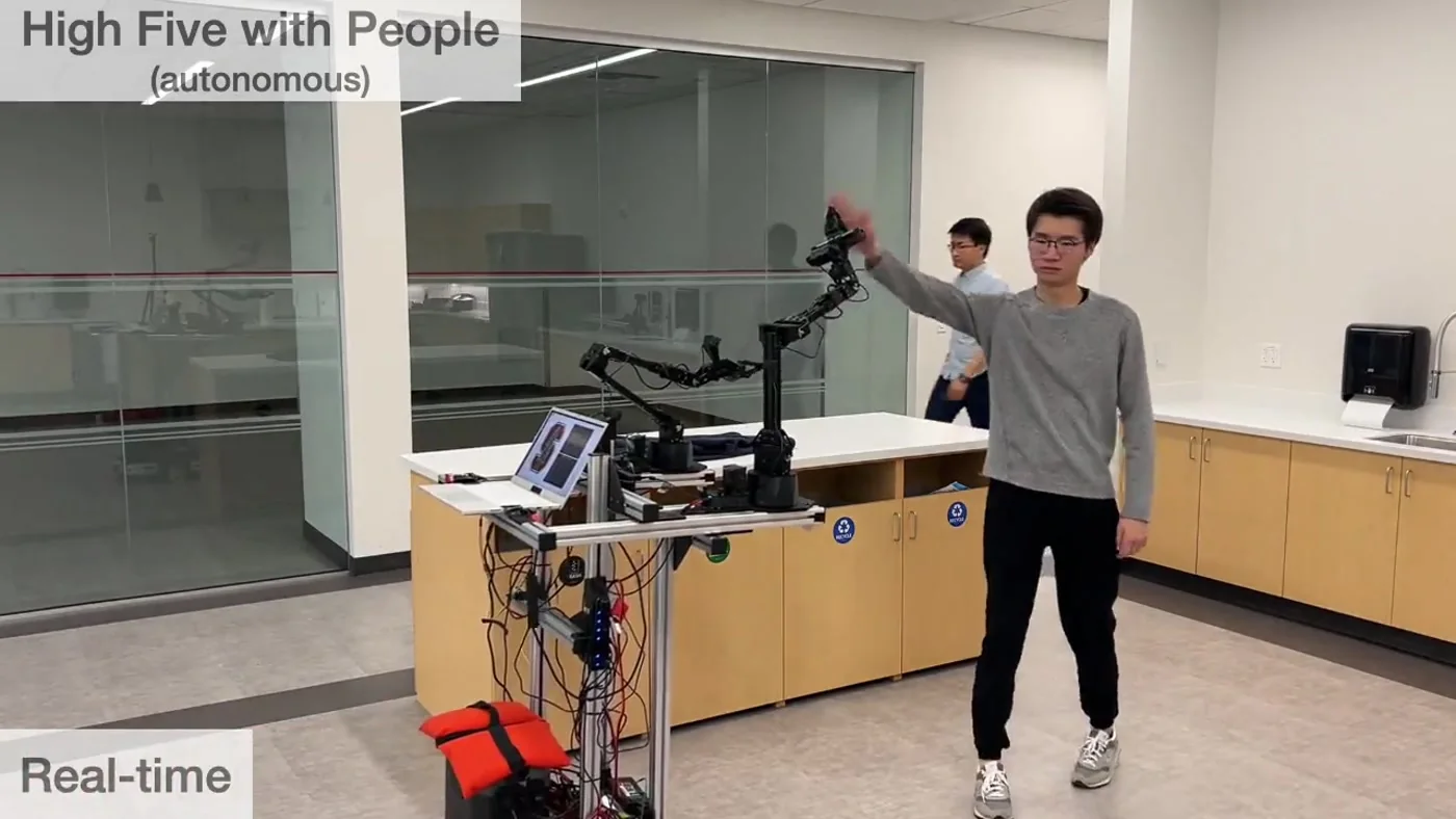 Mobile ALOHA raises a manipulator to high-five a person during an autonomous whole-body interaction demonstration.