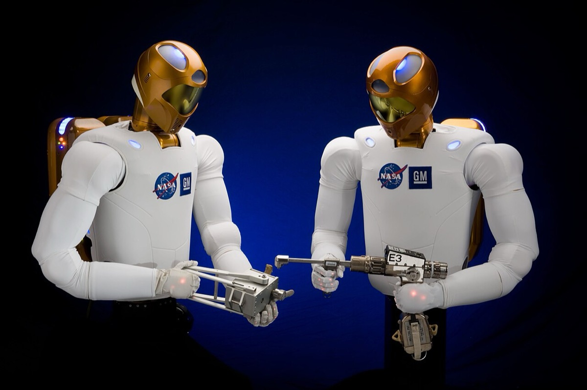 Two NASA Robonaut 2 humanoid research robots using tools in a laboratory demonstration